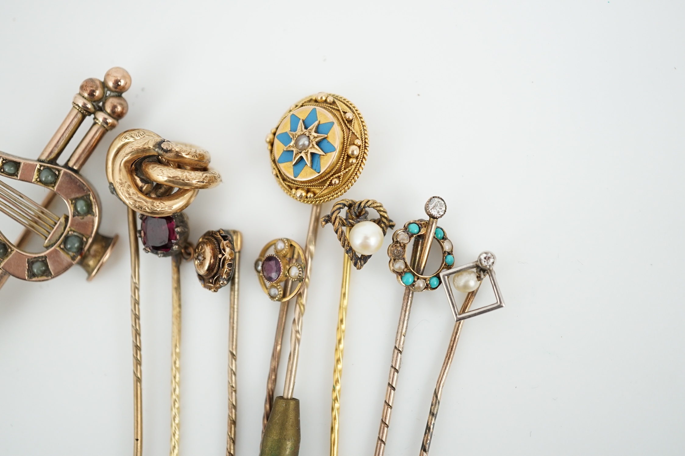 A Victorian yellow metal and cat's eye chrysoberyl set lyre bar brooch, 51mm and eight assorted gem set yellow metal stick pins including enamel and diamond set.